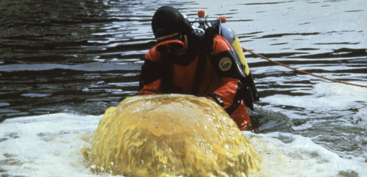 : Wolfgang Pekny im Taucheranzug befestigt ein Gelenk am Abwasserrohr einer Papierfabrik, um das in den Fluss geleitete Abwasser sichtbar zu machen, 1989. Foto © Greenpeace Central and Eastern Europe